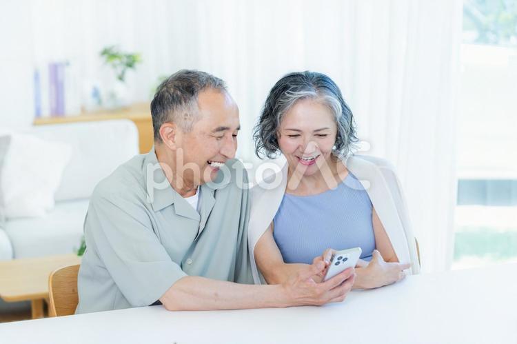 リビングでスマホを見るシニア夫婦 スマホ,笑顔,シニアの写真素材