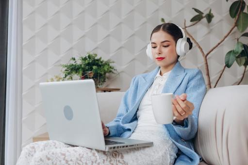 パソコンを見てマグカップを持っている女性 女性,スーツ,水色の写真素材