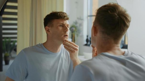 洗面所の鏡で顎をチェックする男性 男性,外国人,欧米人の写真素材