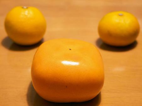 つやつや柿と黄色い果実の写真