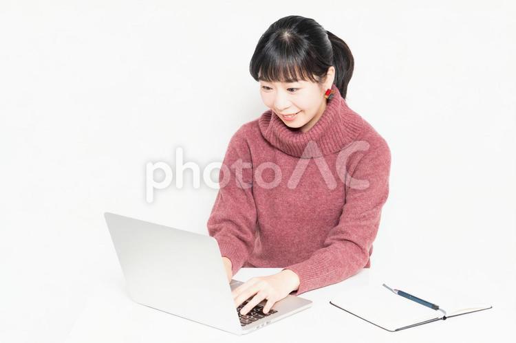 白背景の前に座ってノートパソコンを使う女性 女性,ビジネス,パソコンの写真素材