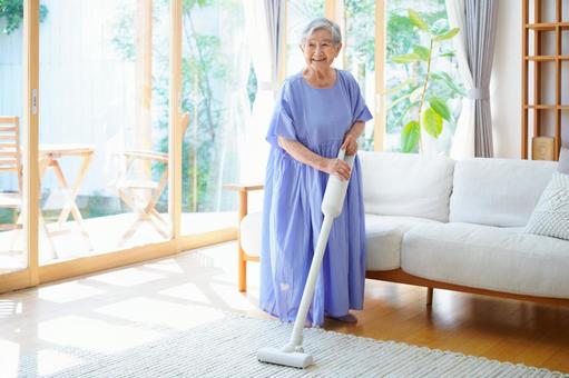 白い掃除機を持ち見つめるおばあちゃん 女性,掃除,掃除機の写真素材