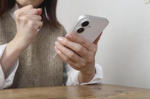 スマホを見てガッツポーズをする女性 スマホ,女性,喜びの写真素材