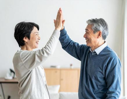 ハイタッチするシニア夫婦 ハイタッチするシニア夫婦の写真