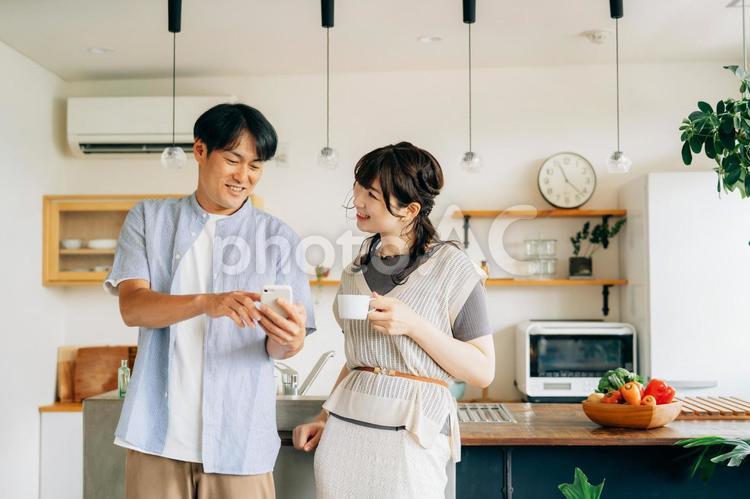 キッチンの前でスマホを使う男女 スマホ,夫婦,スマートフォンの写真素材