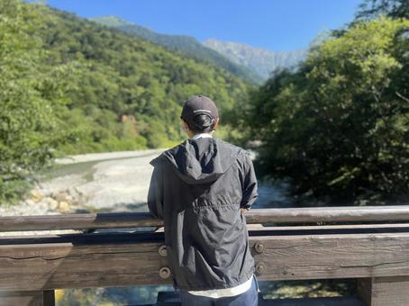 橋から山を眺める男性 橋から山を眺める男性 上高地,川,綺麗の写真素材