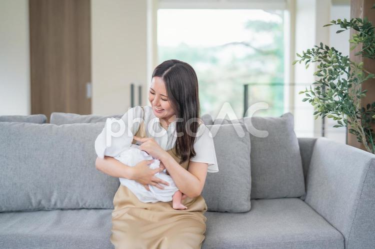 ソファーで赤ちゃんを抱っこする女性 赤ちゃん,ママ,育児の写真素材