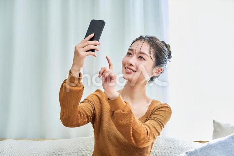 部屋でスマートフォンを操作する若い女性 女性,若い,スマートフォンの写真素材