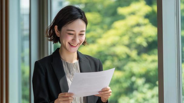嬉しい通知を読む若手ビジネスパーソンの写真