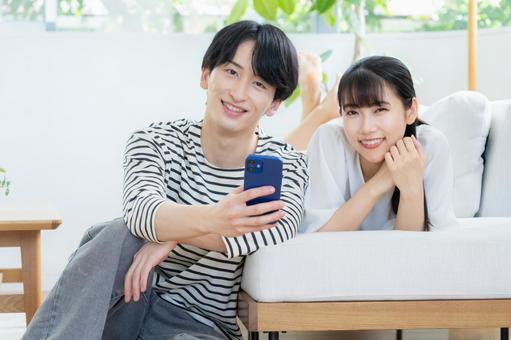 リビングでスマホを見る若いカップル リビングでスマホを見る若いカップル 夫婦,カップル,リビングの写真素材
