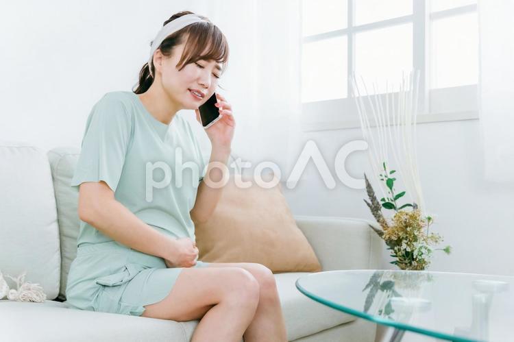 陣痛がきて電話するアジア人女性（妊婦）　 陣痛,流産,破水の写真素材