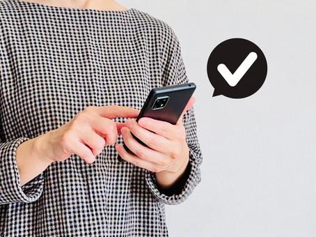 スマホから申請する女性 スマホから申請する女性 スマホ,女性,チェックマークの写真素材