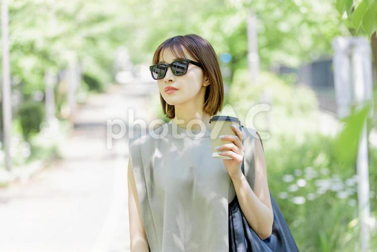 新緑の中コーヒーを飲む若い女性 女性,外出,お出かけの写真素材