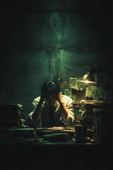 書類に埋もれて頭を抱える男性 書類に埋もれて頭を抱える男性の写真