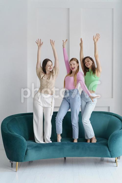 ソファの上ではしゃぐ3人の女性 女性たち,女性,外国人の写真素材