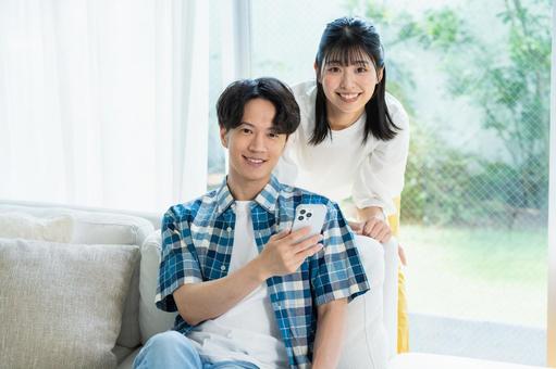 リビングでスマホを見るカップル スマホ,笑顔,カップルの写真素材