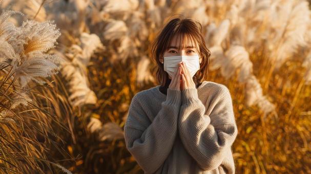 秋風に揺れるススキとマスク姿の女性 秋風に揺れるススキとマスク姿の女性の写真