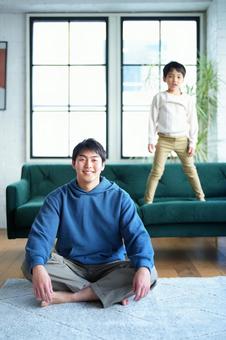 ソファーに仁王立ちの男の子とあぐらの男性 ソファーに仁王立ちの男の子とあぐらの男性 親子,男の子,小学生の写真素材