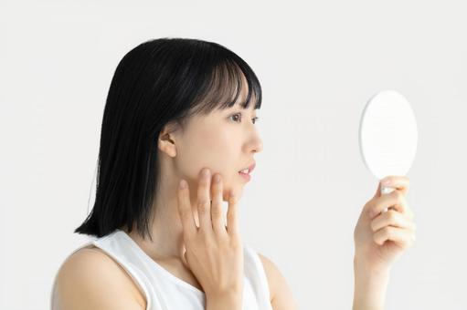 鏡で肌をチェックする若い女性 鏡で肌をチェックする若い女性 女性,美容,健康の写真素材