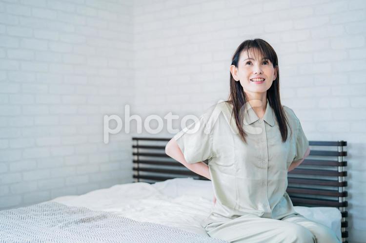腰を押さえるミドル世代の女性（笑顔） 腰痛,骨粗鬆症,治るの写真素材