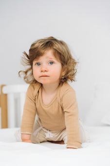 ベッドに手を付きポーズするくせ毛の子供 ベッドに手を付きポーズするくせ毛の子供 赤ちゃん,かわいい,ハイハイの写真素材