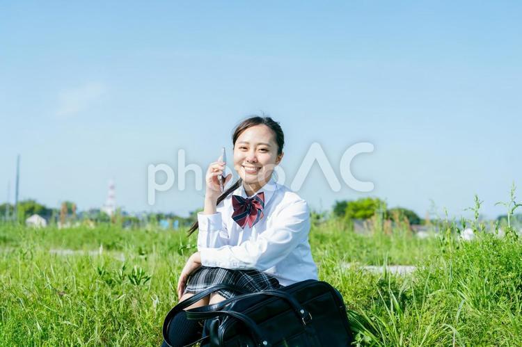 青空の下でスマホを持つ女子高校生 スマホ,高校生,女性の写真素材