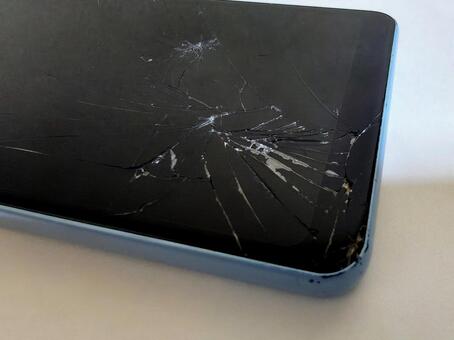 画面にヒビが入ったスマホ（水色） スマートフォン,ひび割れ,落下の写真素材