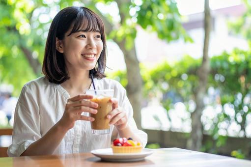 カフェのテラス席でお茶をする女性 カフェのテラス席でお茶をする女性の写真