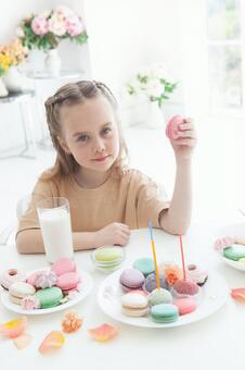 カメラ目線でピンクのマカロンを持つ女の子 女の子,マカロン,持つの写真素材
