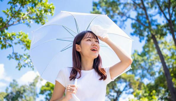 日傘をさして白いハンカチで汗を拭く女性 日傘をさして白いハンカチで汗を拭く女性の写真