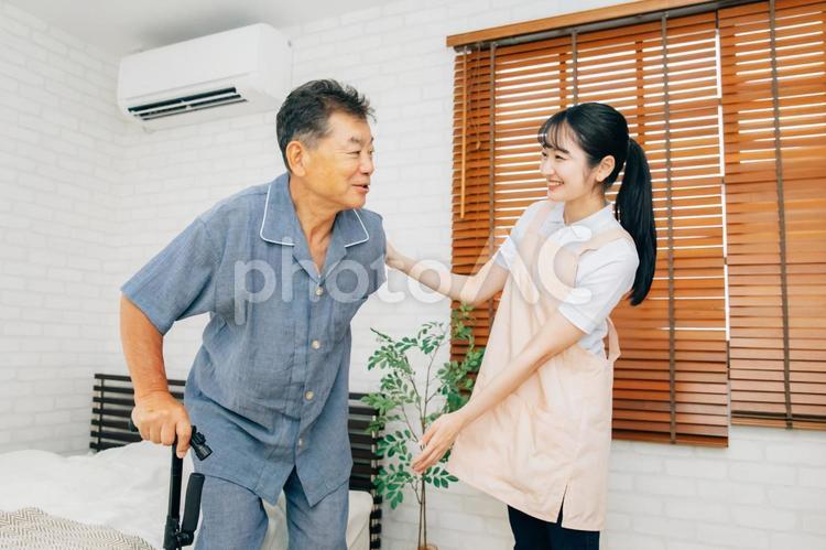 杖を使う高齢者男性と女性スタッフ 訪問介護,介護,高齢者の写真素材