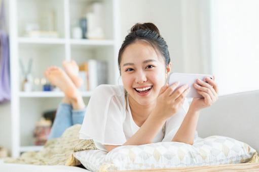 スマホで動画を見る若い女性 スマートフォン,笑顔,動画の写真素材