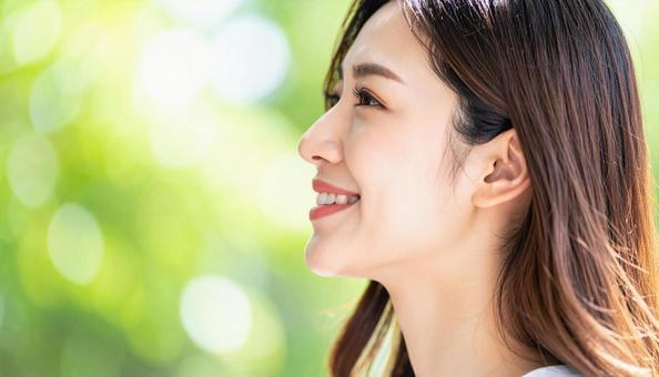 屋外で笑顔を見せる若い女性の横顔 屋外で笑顔を見せる若い女性の横顔の写真