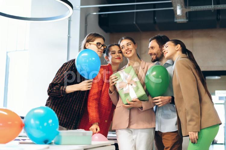 オフィスで女性の誕生日を祝って寄り添っている同僚たち ビジネス,ビジネスマン,ビジネスウーマンの写真素材