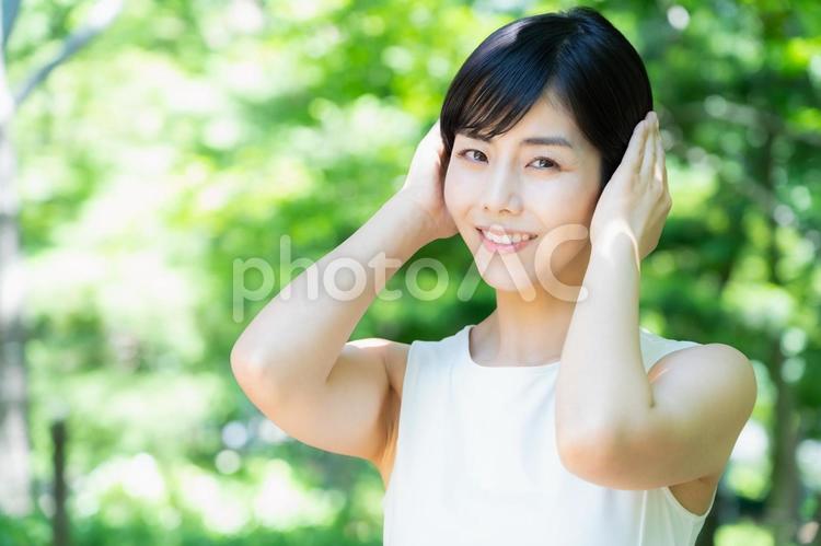 緑の中でヘアケアをする若い女性 ヘアケア,育毛,スキンケアの写真素材