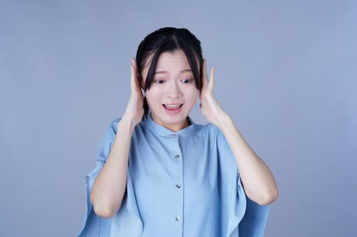 両耳をふさいだ青い服の女性 女性,驚く,困るの写真素材