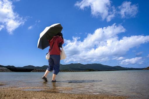 <素材>夏の海水浴場で遊ぶ日傘の女性 <素材>夏の海水浴場で遊ぶ日傘の女性 女性,人物,夏の写真素材