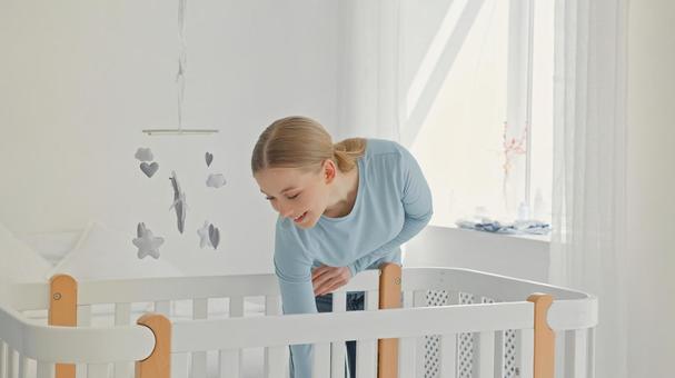 ベビーベッドの中に手を伸ばす笑顔の女性 ベビーベッドの中に手を伸ばす笑顔の女性 女性,見る,微笑むの写真素材