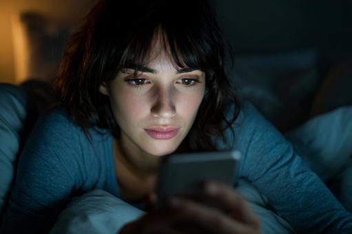 画面の光に照らされる女性の憂鬱な表情 画面の光に照らされる女性の憂鬱な表情の写真