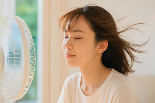 扇風機の風を浴びて涼む女性・夏の暑さ対策 扇風機の風を浴びて涼む女性・夏の暑さ対策の写真