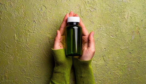 薬の入ったガラスの薬瓶を持つ女性の手 薬の入ったガラスの薬瓶を持つ女性の手の写真