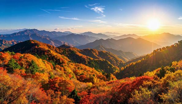 紅葉に染まったモミジの林と山と秋空 紅葉に染まったモミジの林と山と秋空の写真