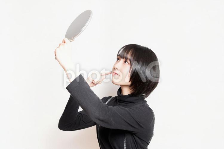 手鏡で顔を見ている若い女性 鏡,女性,若いの写真素材