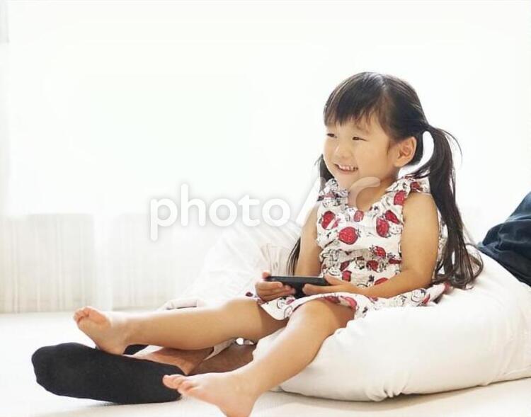 父の膝の上でスマホを見る女の子 嬉しい,休日,仲良しの写真素材