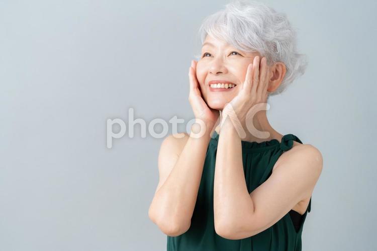 グレーバックでスキンケアをするシニア女性 ビューティー,女性,シニアの写真素材