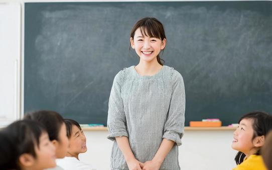 黒板の前に立つ若い女性の小学校教諭 黒板の前に立つ若い女性の小学校教諭の写真