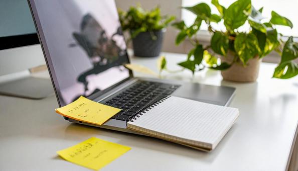 付箋がついたノートとパソコンデスクの写真