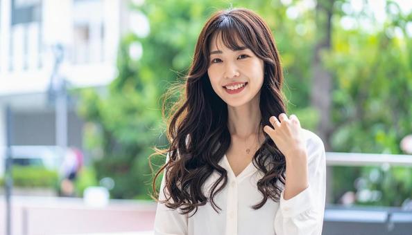 長い黒髪を触る笑顔の女性 長い黒髪を触る笑顔の女性の写真