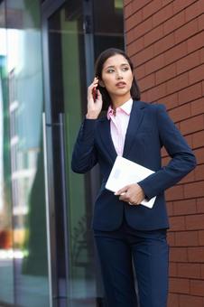 オフィスビルの外でスマートフォンで電話するビジネスウーマン ビジネスウーマン,ビジネス,女性の写真素材