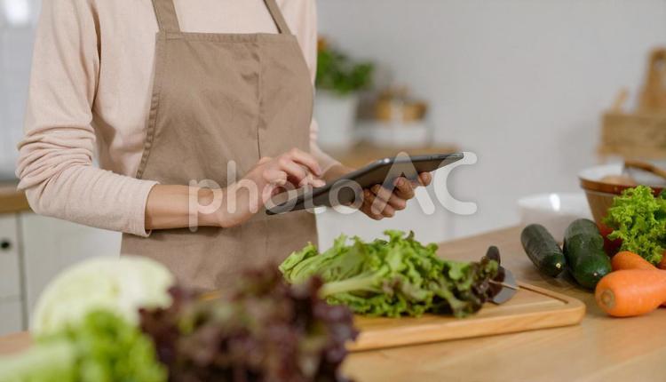 台所でレシピをタブレットで確認する女性 手料理,上半身,日本人の写真素材